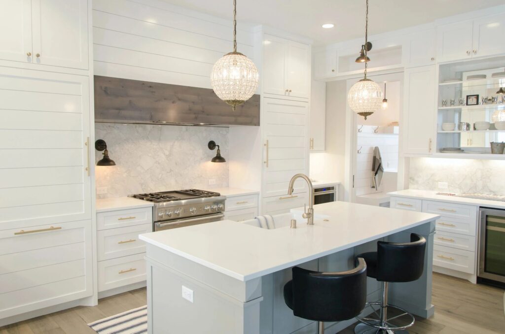 Modern white kitchen with island and pendant lights.